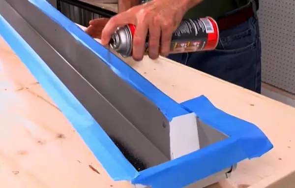 Homeowner applying gutter sealant to a leaking seam with a caulking gun during a roof repair project