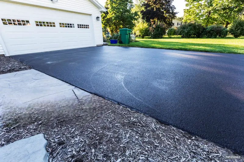 Beautiful residential asphalt driveway in good condition with well-maintained surface and landscaping