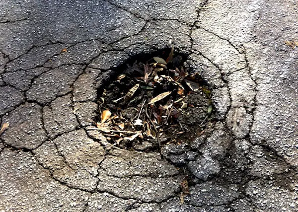 Deteriorated asphalt driveway showing alligator cracking and potholes requiring replacement