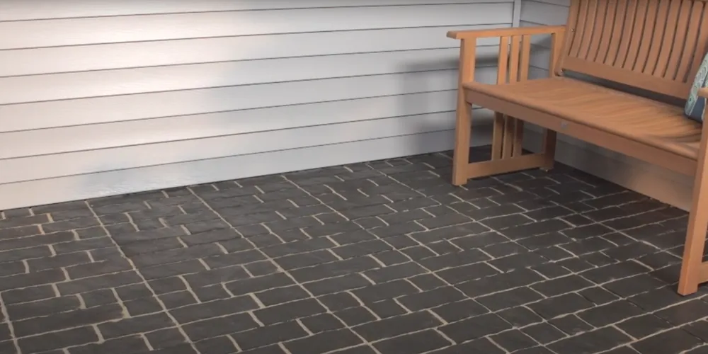 Un patio avec des pavés en interlock, avec un banc de jardin placé sur la surface